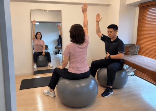 櫻花堂治療院でバランスボールを使ったトレーニング指導を受ける女性